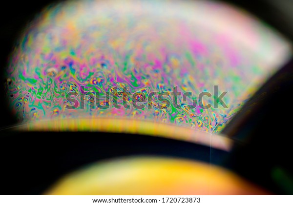 Psychedelic abstract planet from soap bubble,\
Light refraction on a soap bubble, Macro Close Up moving particles\
Rainbow colors on a black background. Model of Space or planets\
universe cosmic\
galaxy.