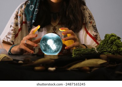 psychic woman looks into the future from the magic sphere. Mysterious magnificent fortune teller in ethnic dress with magical blue crystal ball.
