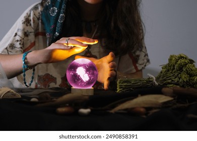 psychic woman looks into the future from the magic sphere. Mysterious magnificent fortune teller in ethnic dress with magical purple crystal ball.