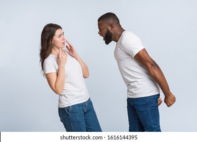 Psychological abuse. Angry black man emotionally shouting at his scared girlfriend, blaming her for everything, light background with free space