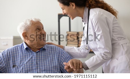 Psychological support. Friendly medical worker caregiver help assist older male with hard diagnosis. Smiling female doctor talk with old man patient express empathy share positive emotions hold hand