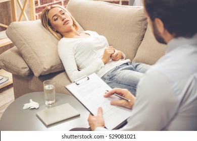 At The Psychologist. Beautiful Young Woman Is Lying On Couch And Talking While Doctor Is Making Notes