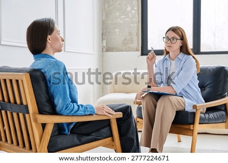 Psychologist with glasses taking notes during counseling session with young female client