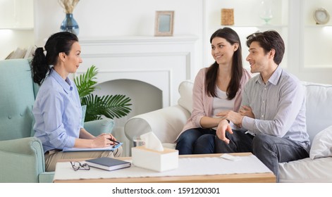 Psychologist and happy couple after effective marital therapy, man and woman cuddling and smiling to psychotherapist in office, panorama with empty space