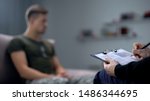 Psychologist making notes during therapy session with sad male soldier, PTSD