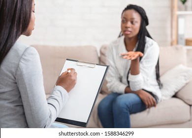 Psychologist taking notes during therapy session with her emotional female patient that talking with about her problems and actively gesturing