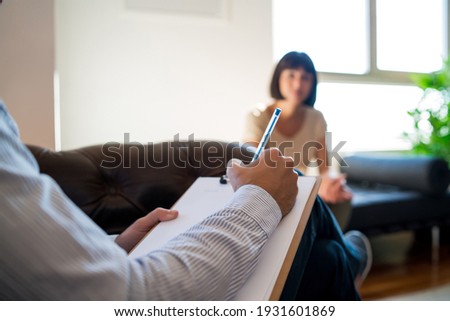 Psychologist taking notes during therapy session.