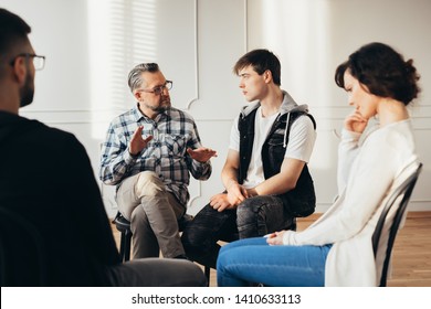 Psychologist talking about twelve-step program to addicted man during group support meeting