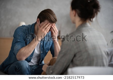 Psychologist talking with patient on therapy session. Depressed man speaking to a therapist while she is taking notes