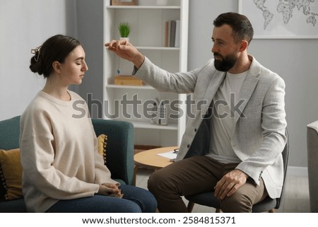 Psychologist using pendulum while working with patient during hypnosis session indoors