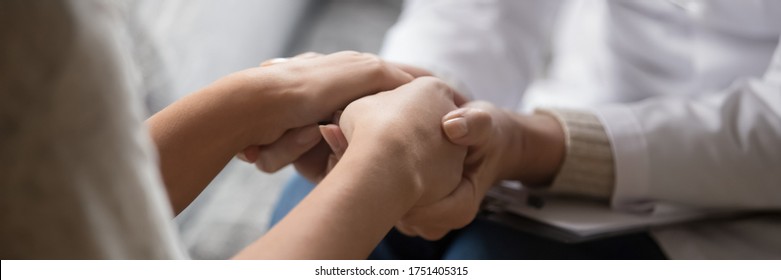 Psychologist in white coat holding hands of woman patient provide professional aid psychological help close up, show support express empathy concept. Horizontal photo banner for website header design - Powered by Shutterstock