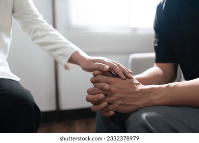 Psychologist woman touching hands to encouraging man with mental health problem in therapy center. - Shutterstock ID 2332378979