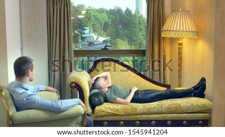 psychologist works with a young bald woman lying on a sofa in a stylish office