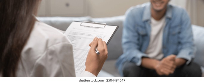 Psychology, depression. Happy smile asian young man patient mental therapy explain symptom with psychologist while doctor woman taking notes at clinic. Psychologist with sick mental health person. - Powered by Shutterstock