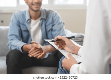 Psychology, depression. Happy smile asian young man patient mental therapy explain symptom with psychologist while doctor woman taking notes at clinic. Psychologist with sick mental health person. - Powered by Shutterstock