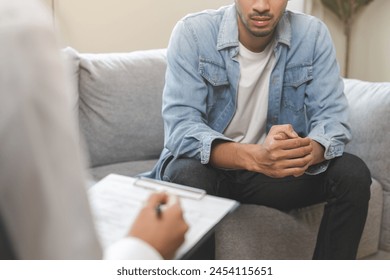 Psychology, depression. Suffer asian young man consultation with psychologist while patient counseling mental therapy, doctor hand taking notes at clinic. Psychologist with sick mental health person. - Powered by Shutterstock