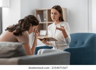 psychology, mental health and people concept - psychologist with notebook talking to stressed woman patient at psychotherapy session