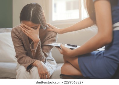 Psychology, sad asian young woman, girl cover face with hand, consulting with psychologist, psychiatrist while patient counseling mental with doctor woman taking notes at clinic. Encouraging, therapy. - Powered by Shutterstock