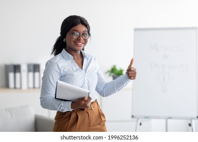 Psychology Teacher Or Business Coach Giving Seminar Or Presentation, Showing Thumb Up Gesture At Office. Black Female Lecturer Recommending Training Course On Personal Growth And Motivation