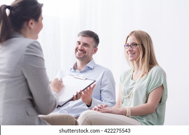 Psychotherapist filling in questionnaire on psychotherapy session with happy young marriage
