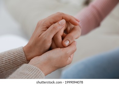 Psychotherapist holding patient's hand indoors, closeup view