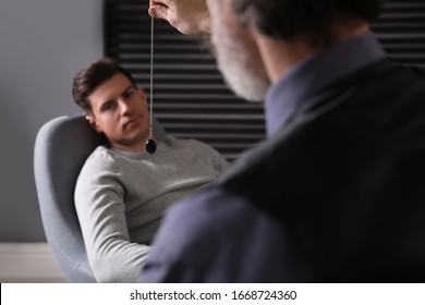 Psychotherapist using pendulum during hypnotherapy   session in office - Powered by Shutterstock