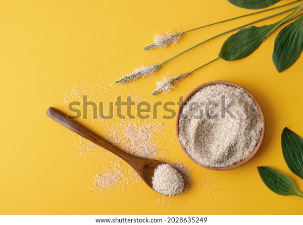Psyllium, isfagula plant product is the husk of plantain\
seeds in a plate on a yellow background. Useful dietary supplement,\
superfood. Top view, horizontal orientation, without people, copy\
space. 