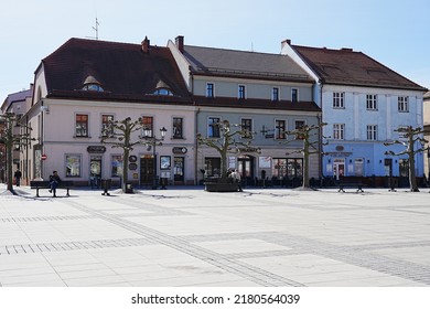 PSZCZYNA, POLEN, MÄRZ 2022: Drei Häuser auf dem Platz im europäischen Stadtzentrum, klarer blauer Himmel in warmer sonniger Frühlingstag.