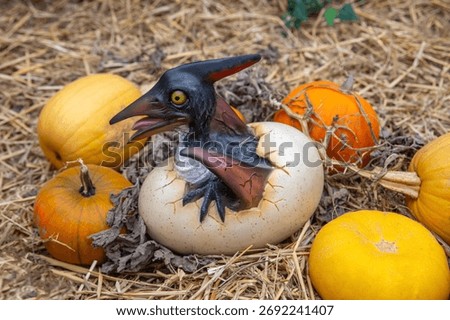 A Pterodactyl dinosaur hatching from an egg, surrounded by pumpkins.