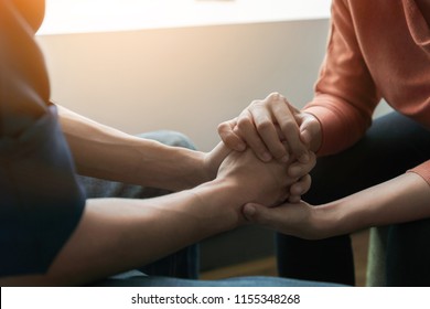 PTSD Mental health concept, Psychologist sitting and touch hand young depressed asian man for encouragement near window with low light environment.Selective focus. - Shutterstock ID 1155348268