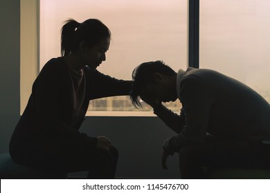 PTSD Mental health concept, Young depressed asian man talking with psychologist sitting near window in dark room at evening time with low light environment.Selective focus.
