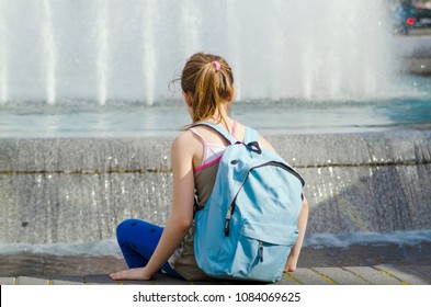 Puberty Little Girl Sitting And Look In To Water Fountain, Rest And Refreshing After School.Back Of Child Girl With Back Pack Anxiety Single And Pensive On Warm Day.