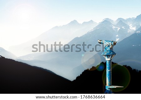 Public binoculars and Mountain Silhouettes at Sunrise. Foresight and vision for new business concepts and creative ideas. Alps, Trentino, South Tyrol, Italy.