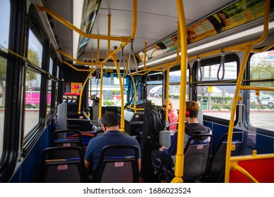 Public bus interior. Yellow handrails and a few passengers sitting. Miami, Florida. March 12, 2020 