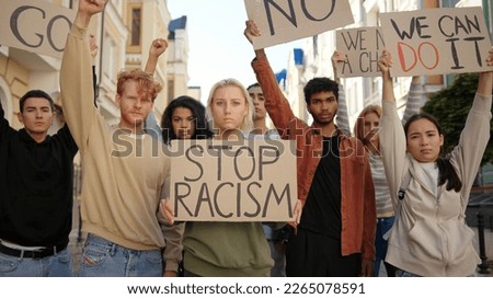 Public demonstration at street against racism with slogans on posters. Multiethnic people protest.