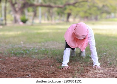 Public Exercise Lifestyle Concept, Fitness Woman Listening Music From Wireless Earphones And Mobile Phone. Young Asian Girl In Muslim Sportswear Doing Push Ups After Workout 