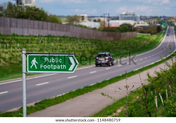 Public\
footpath sign with main road in the\
background