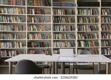 Public library interior with no people and bookshelves. Workplace table, desk with laptop and chairs for studying, college, university, high school students self preparation - Shutterstock ID 2236635283