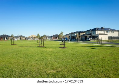 A public park with green lawn/grass and young trees surrounded by new residential houses/Australian homes in a Melbourne's suburb. Tarneit, VIC Australia. Background texture of a
 suburban park. 