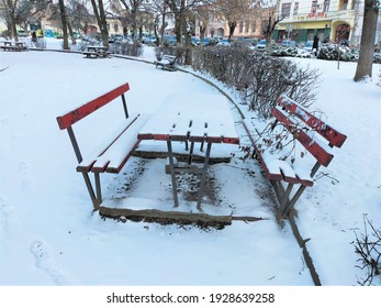 A Public Park Landscape With A Snow-covered Empty Picnic Bench In The Wintertime