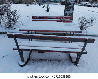 A Public Park Landscape With A Snow-covered Empty Picnic Bench In The Wintertime