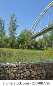 public park with stone wall in the foreground and metal suspension bridge in the background