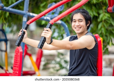 In A Public Park, Young Men Exercise In Sports On An Outdoor Workout Equipment.