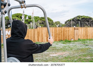 In A Public Park, Young Men Exercise In Sports On An Outdoor Workout Equipment.