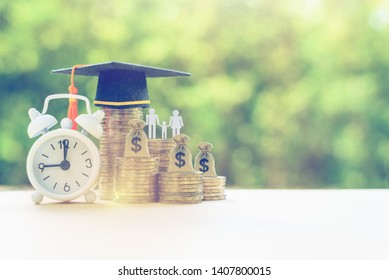 Public School Funding / Education Funding, Financial Concept : Black Graduation Cap / Hat, Family Members And Kid, US Dollar Bag On Rows Of Rising Coins, White Clock On A Table, Green Bokeh Background