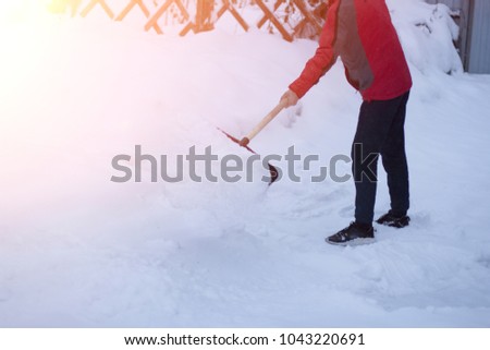 a public service worker in a single shovel snow in the winter blizzard. leaning on his snow with a shovel on his driveway. snowdrifts.
