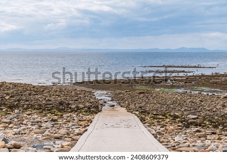 Public Slipway with stones in the low tide on Parton Beach, Cumbria, England, UK