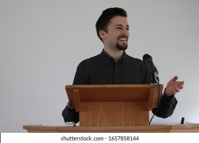 Public Speaking Concept. Attractive Happy Man On A Podium Having A Speech