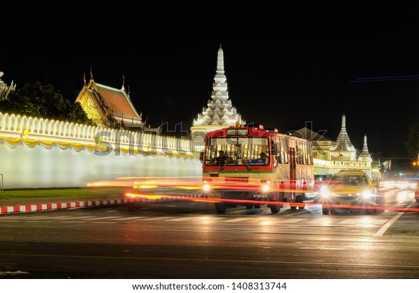 Public transport bus on Traffic road at Wat\
Phra Kaew Temple of the Emerald Buddha,Long exposure light at\
night- BANGKOK, THAILAND - MAY 22,\
2019