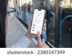 Public transportation app on smartphone in woman hands concept. Bus on station in background